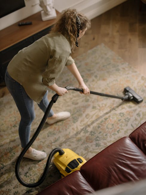 Close-up of a dustpan with a wooden handle and a cream-colored bristle brush, positioned on a wooden floor. The image highlights routine surface cleaning, with the surface appearing clean and dry, ill